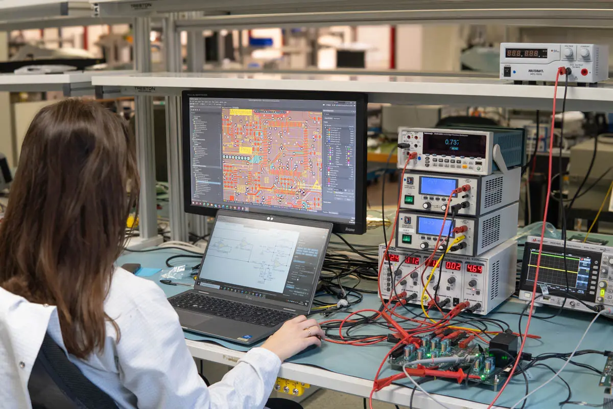 Une ingénieure travaillant sur une paillasse avec divers outils éléctroniques